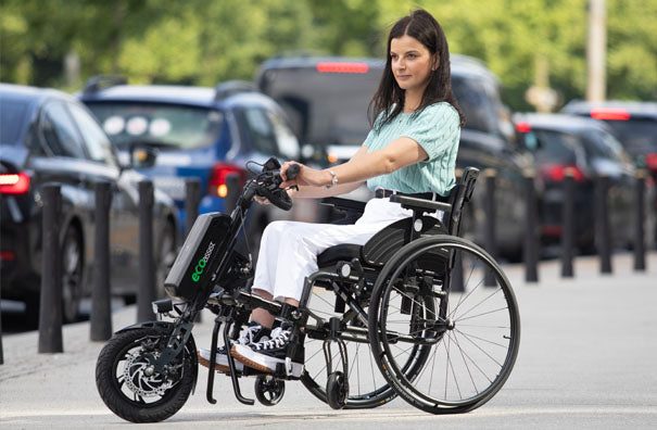 Eco Assist power add-on attached to a manual wheelchair, in use in the city