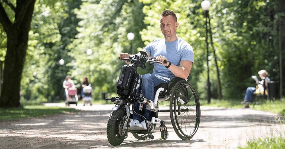 PAWS power add-on attached to a manual wheelchair, in use in a park